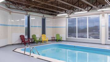 An indoor swimming pool with a tiled floor, a metal roof, and large windows.