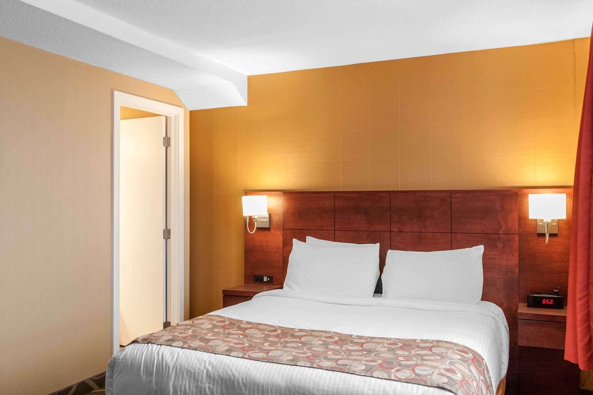 Habitació d'hotel amb un llit gran, dues taules de nit i un panell de fusta al capçal.