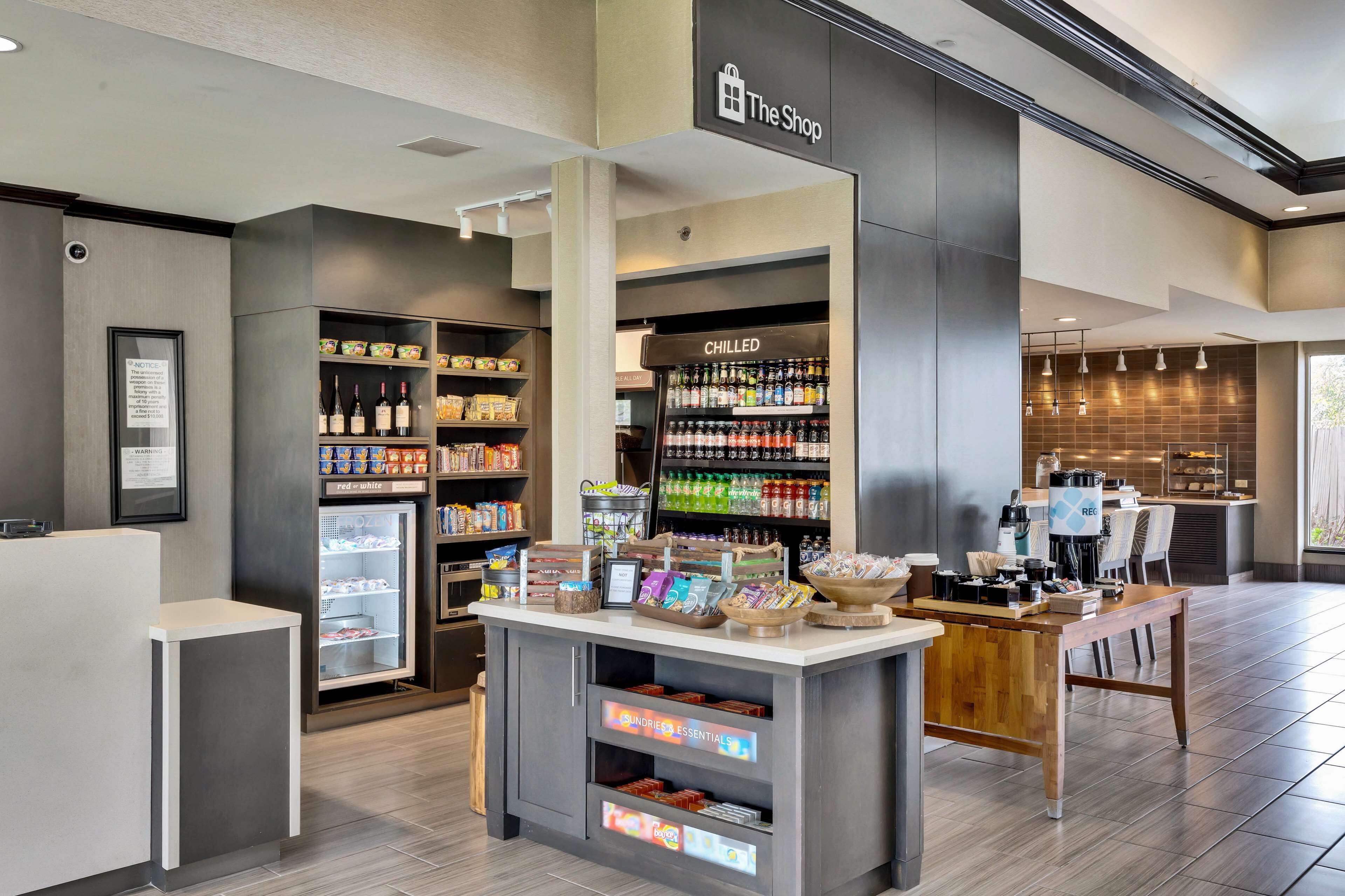 A modern retail area with a chilled beverage display, snack shelves, and a coffee station.