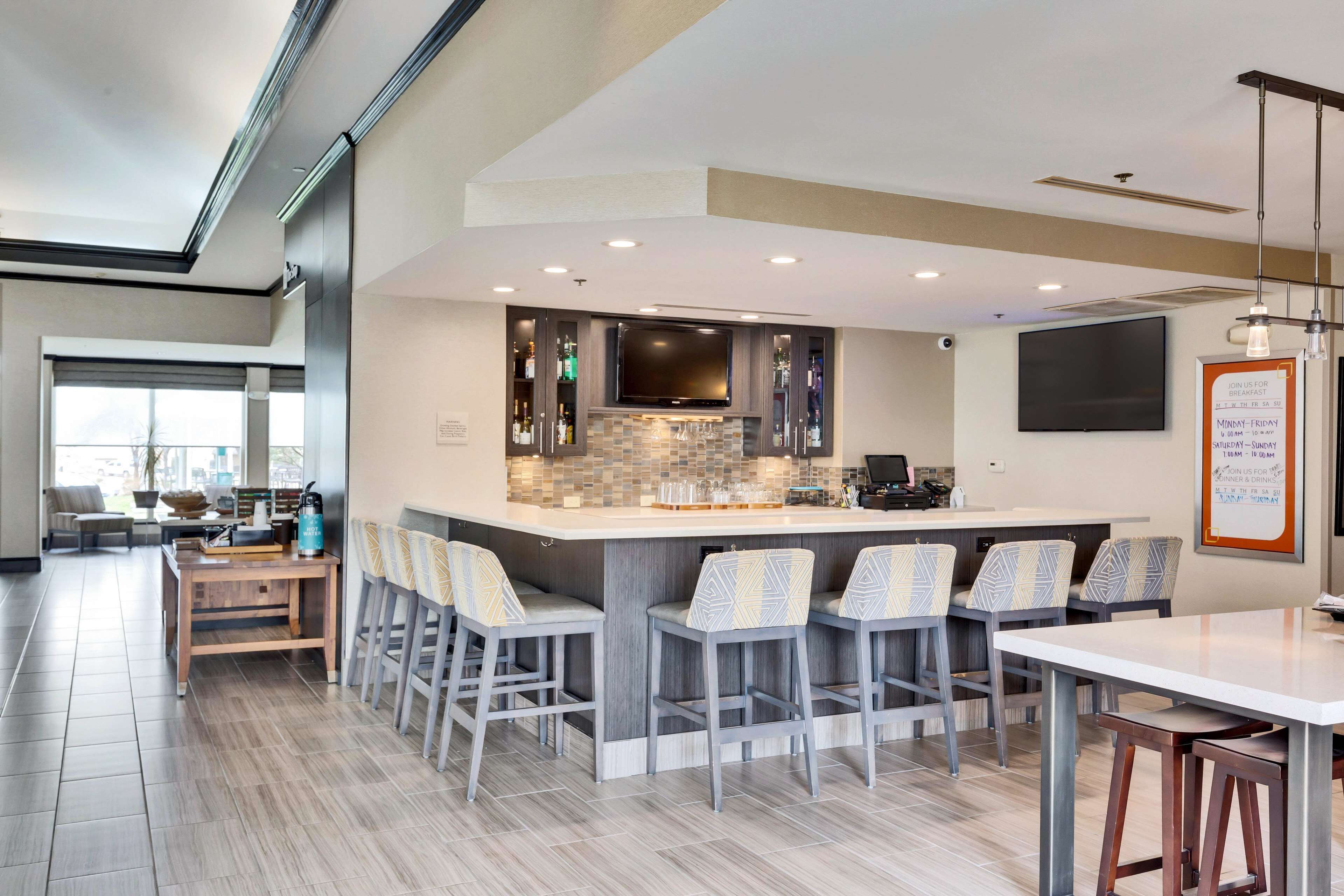 A modern kitchen with a central island, bar stools, and a flat-screen TV.