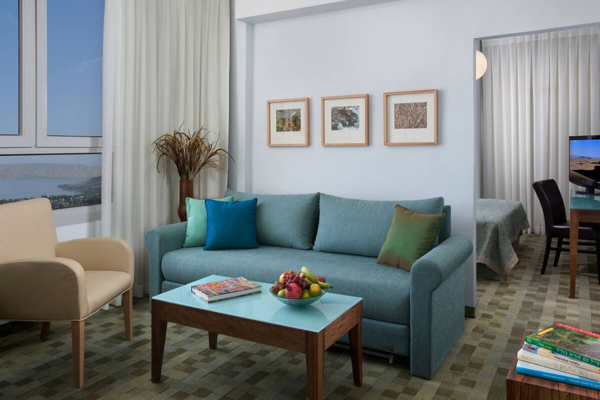Una sala de estar moderna con sofá, sillón, mesa de centro y un comedor con mesa y sillas.