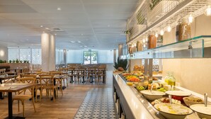 Uma área de buffet com diversos alimentos e um espaço de refeições com mesas e cadeiras de madeira.