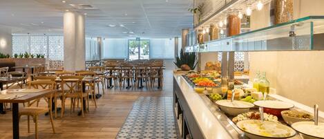 Un área de bufé con diversas opciones de comida y un espacio de comedor con mesas y sillas de madera.