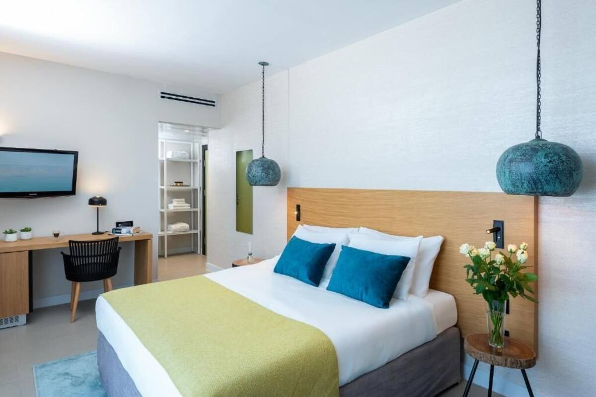 Una habitación de hotel moderna con una cama grande, un escritorio y un televisor.