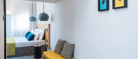 Un dormitorio moderno con una cama, un banco y dos obras de arte enmarcadas en la pared.