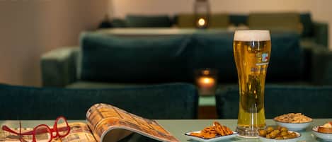 A table with a beer glass, a magazine, and snacks in bowls.