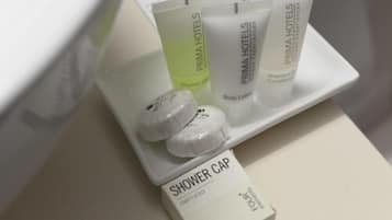 Un meuble de salle de bain contenant des articles de toilette, notamment un bonnet de douche, une lotion pour le corps et un shampooing-après-shampooing.