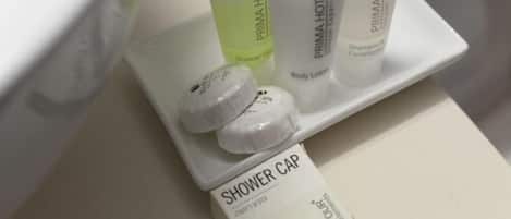 A bathroom counter with toiletries including a shower cap, body lotion, and shampoo conditioner.