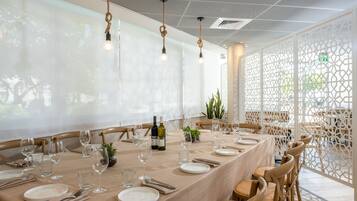 Una larga mesa de comedor preparada para una comida, con sillas, copas de vino y botellas.