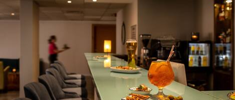 A bar area with a long counter, glasses of drinks, and plates of food.