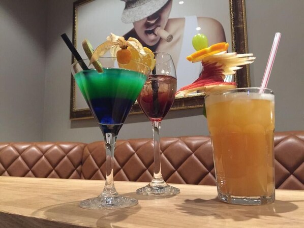 Three drinks on a table with a brown leather couch in the background. - Hotel Am Markt (Nordenham)