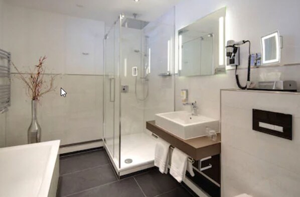 A modern bathroom with a glass-enclosed shower, a sink, and a large mirror. - Hotel Am Markt (Nordenham)