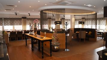 A modern hotel lobby with a wooden reception desk, seating areas, and decorative plants.