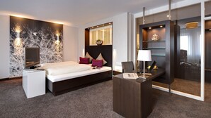 Una habitación de hotel moderna con una cama, una mesita de noche y un escritorio con lámpara.