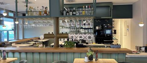 A restaurant interior with a bar area, seating, and a kitchen in the background.