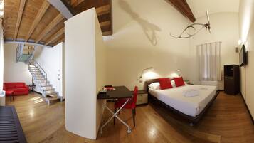 Un dormitorio con cama, escritorio, silla y una escalera que sube a un nivel superior.