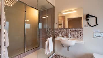 A modern bathroom with a glass-enclosed shower, a white sink, and a large mirror.
