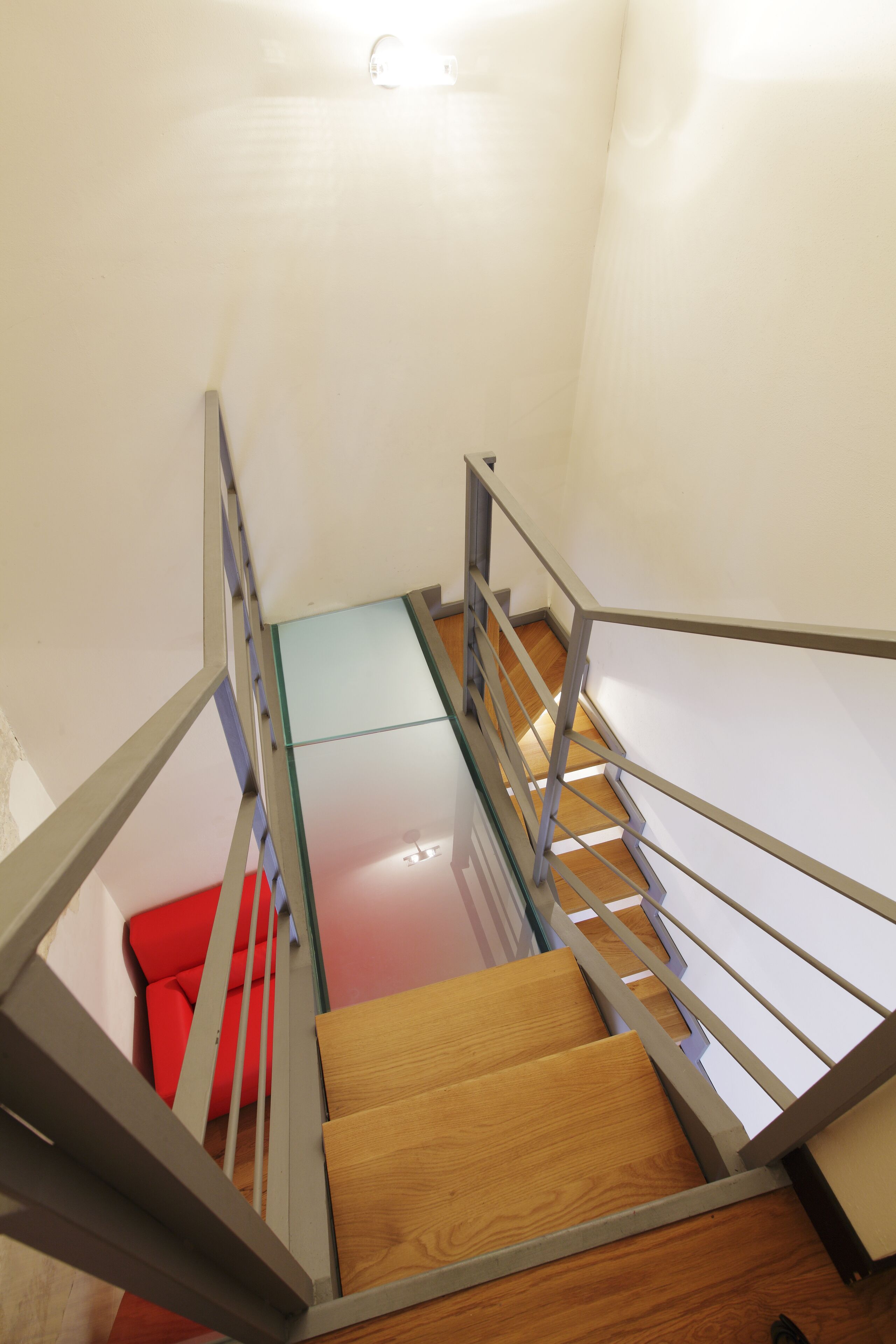 Een moderne trap met glazen balustrades en houten treden.