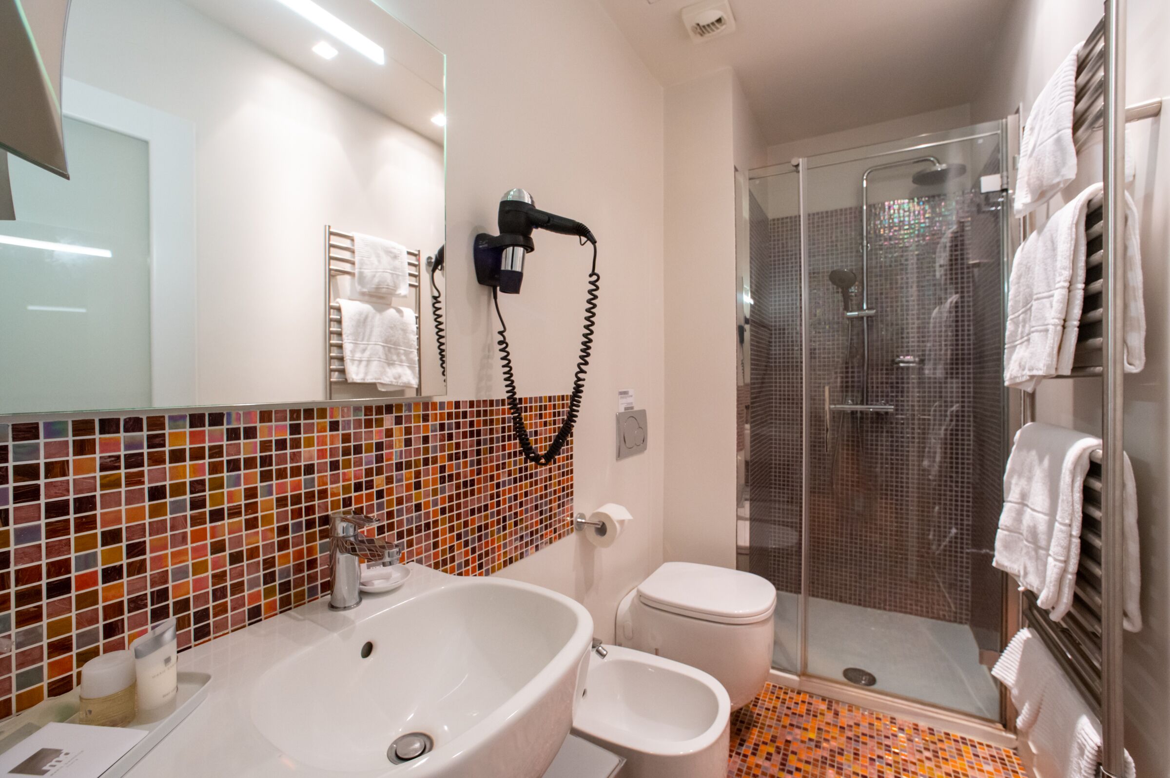 A modern bathroom with a large bathtub, a toilet, and a glass-enclosed shower area.