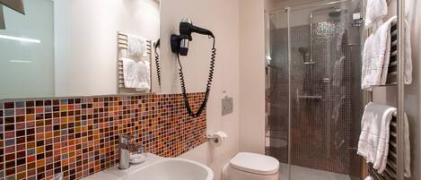 Un baño moderno con una bañera grande, un inodoro y una zona de ducha con mampara de vidrio.