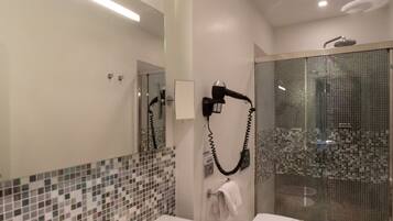 Un baño moderno con un espejo grande, dos lavamanos, un bidé y una ducha con mampara de vidrio.