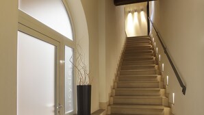 Una escalera con barandilla de madera, una planta en maceta y una puerta con vidrio esmerilado.