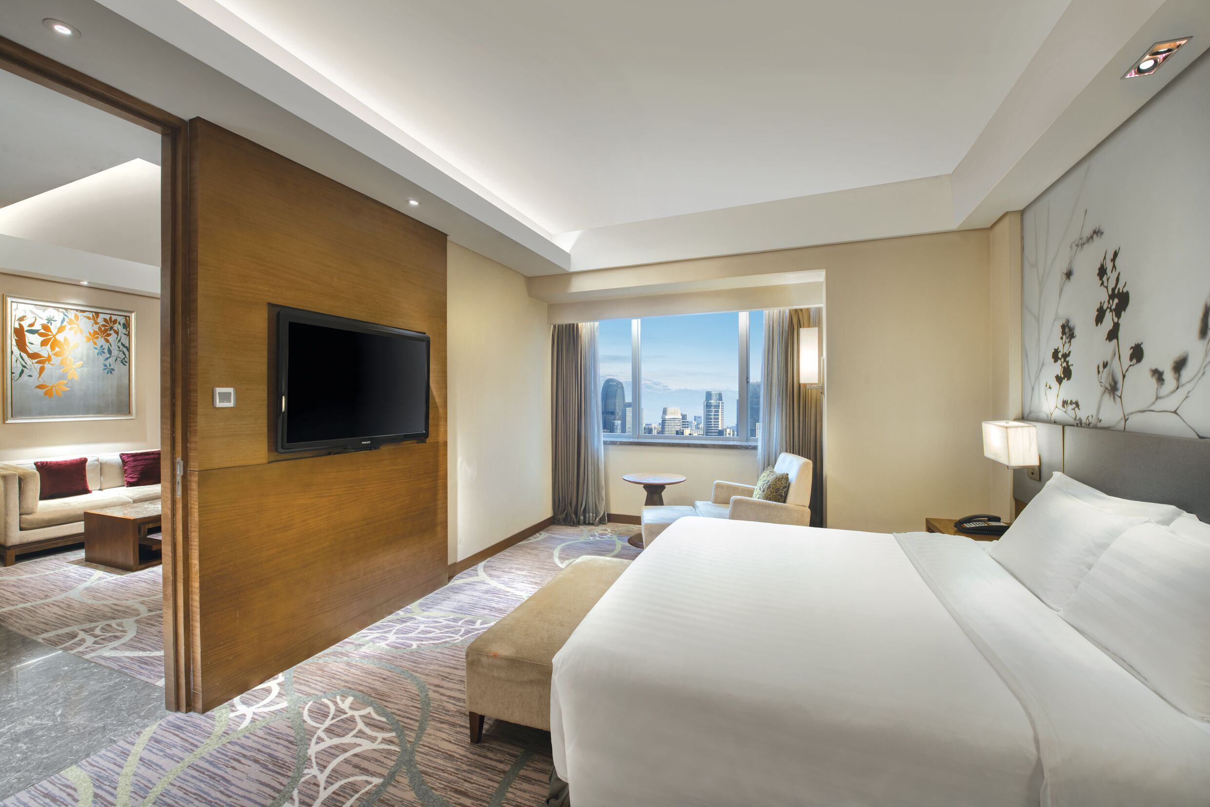 Habitación de hotel con una cama grande, televisión, vistas a la ciudad, un sofá y una mesita.