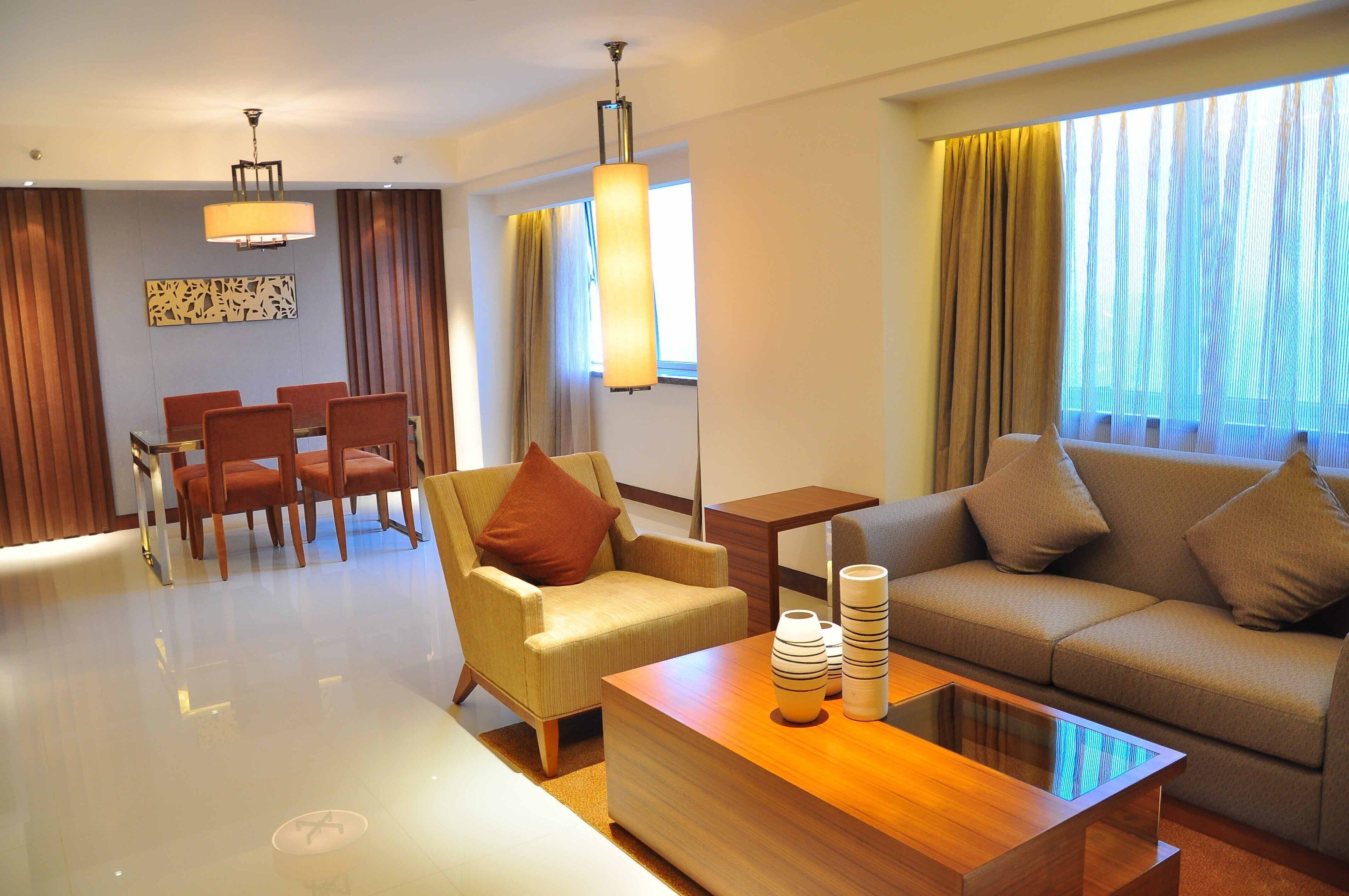 Una habitación de hotel moderna con comedor, sofá y mesa de centro.