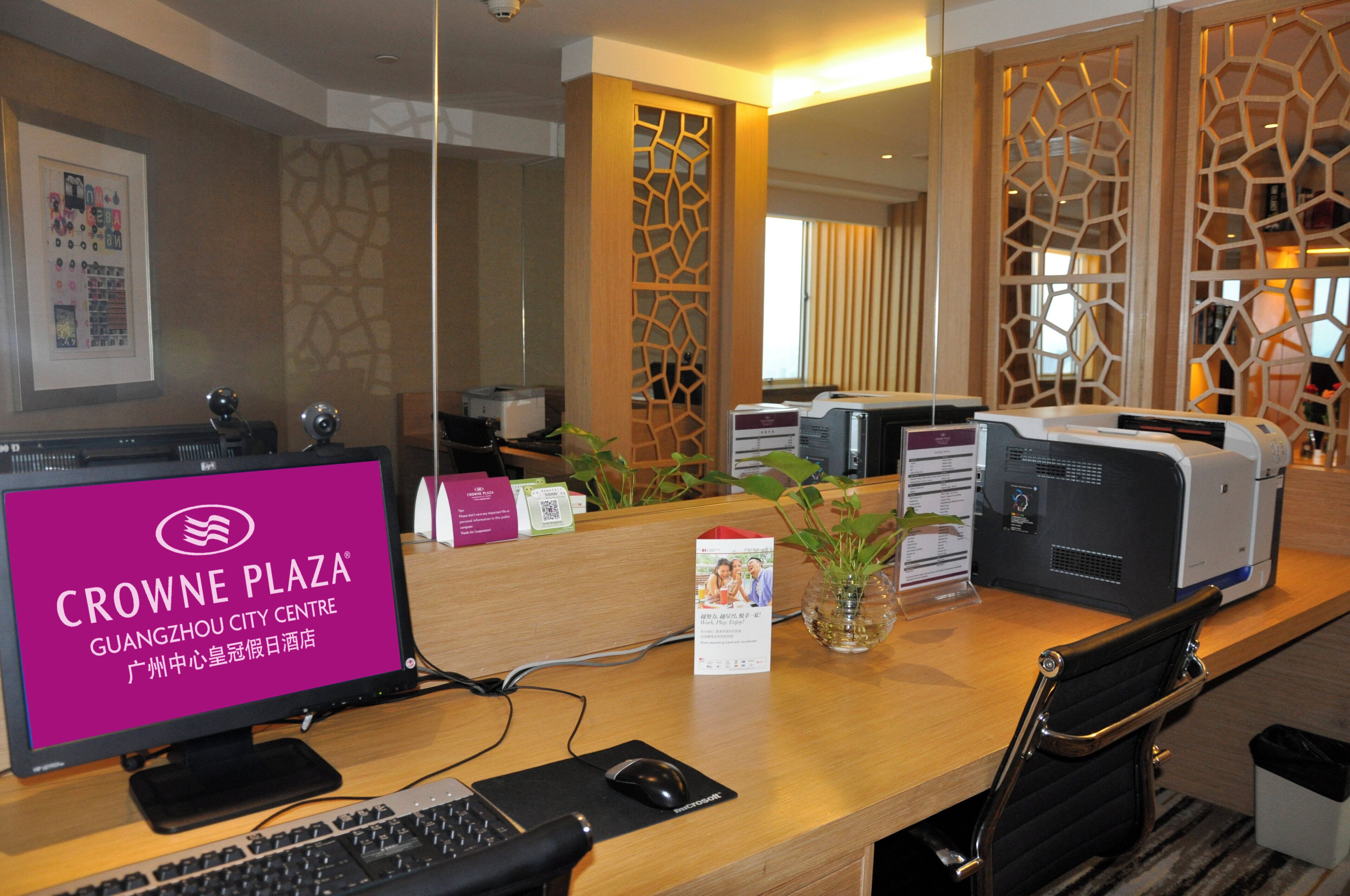 Mostrador de recepción de hotel con computadora, impresora y una planta.