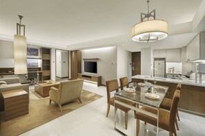 Una habitación de hotel moderna con comedor, televisor y kitchenette.