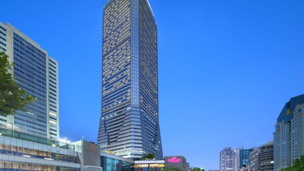 A tall, modern skyscraper with a glass facade, surrounded by other high-rise buildings.