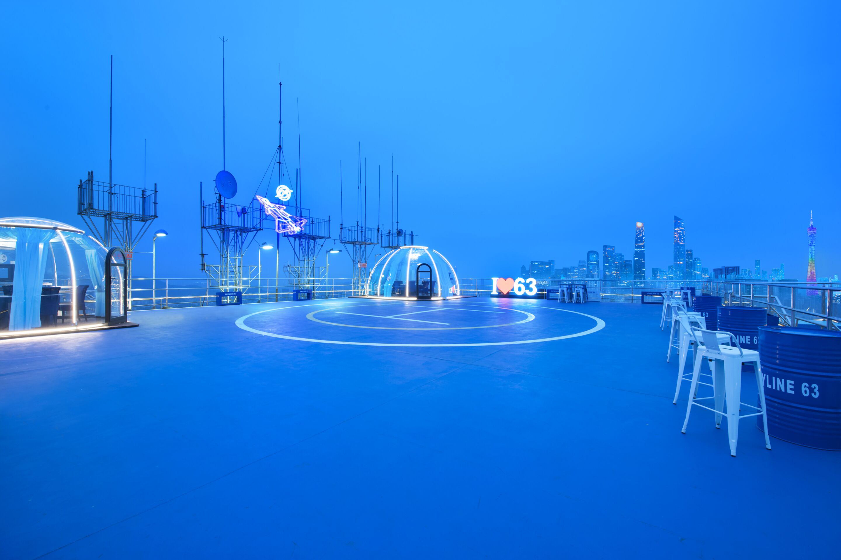 A spacious indoor area with a blue floor, a large circular structure in the center, and a sign reading "LINE 63".