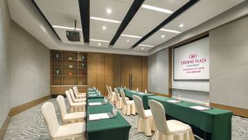 A conference room with multiple tables and chairs, a projector screen, and a presentation on the wall.