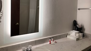 A bathroom with a large mirror, a towel rack, a sink with toiletries, and a shower curtain. - Sleep Inn Louisville Airport (Louisville)