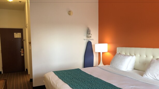 A hotel room with a bed, a nightstand, a lamp, a headboard, and a door. - Sleep Inn Louisville Airport (Louisville)