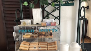A clear display case labeled "FRESH DONUTS" with various donuts and sandwiches inside. - Sleep Inn Louisville Airport (Louisville)