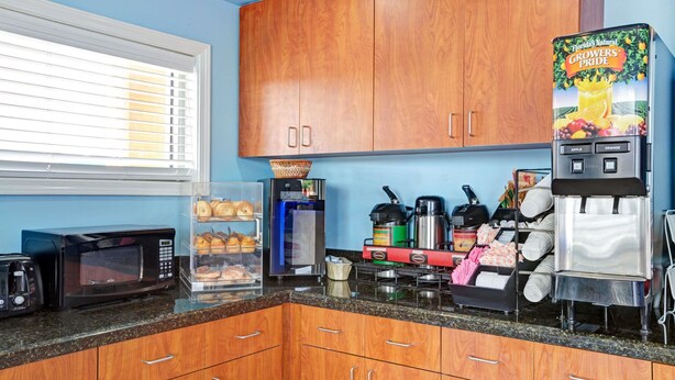 Cocina con armarios de madera, microondas, cafetera y refrigerador con etiqueta Florida's Natural Growers Pride.