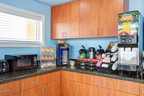 Une cuisine dotée de meubles en bois, d’un four à micro-ondes, d’une machine à café et d’un réfrigérateur portant l’étiquette « Florida’s Natural Growers Pride ».