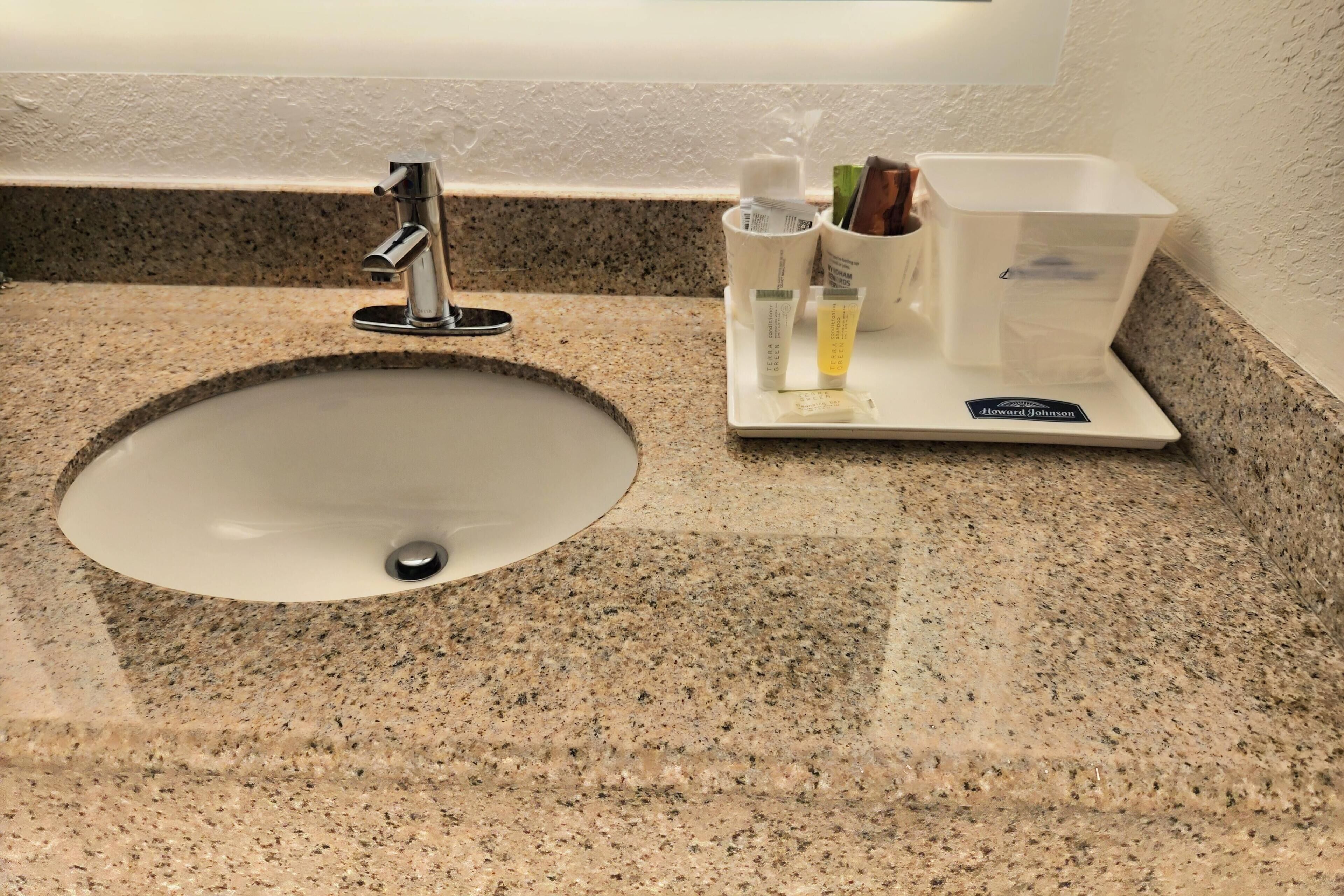 Ein Waschbecken mit Granitplatte, einem Wasserhahn und einer Seifenspender.