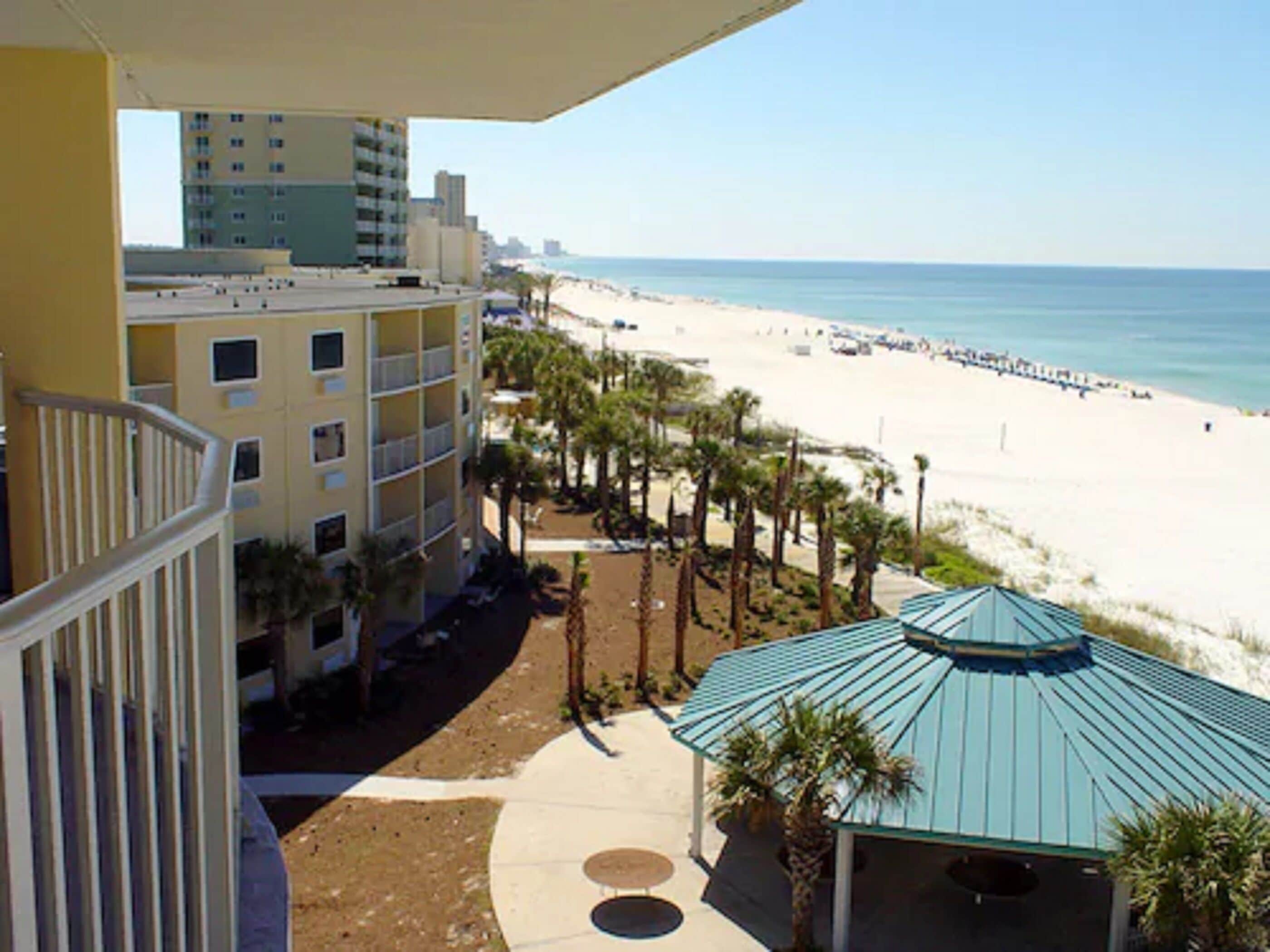 A beachfront hotel with a pool area, palm trees, and a view of the beach and ocean.