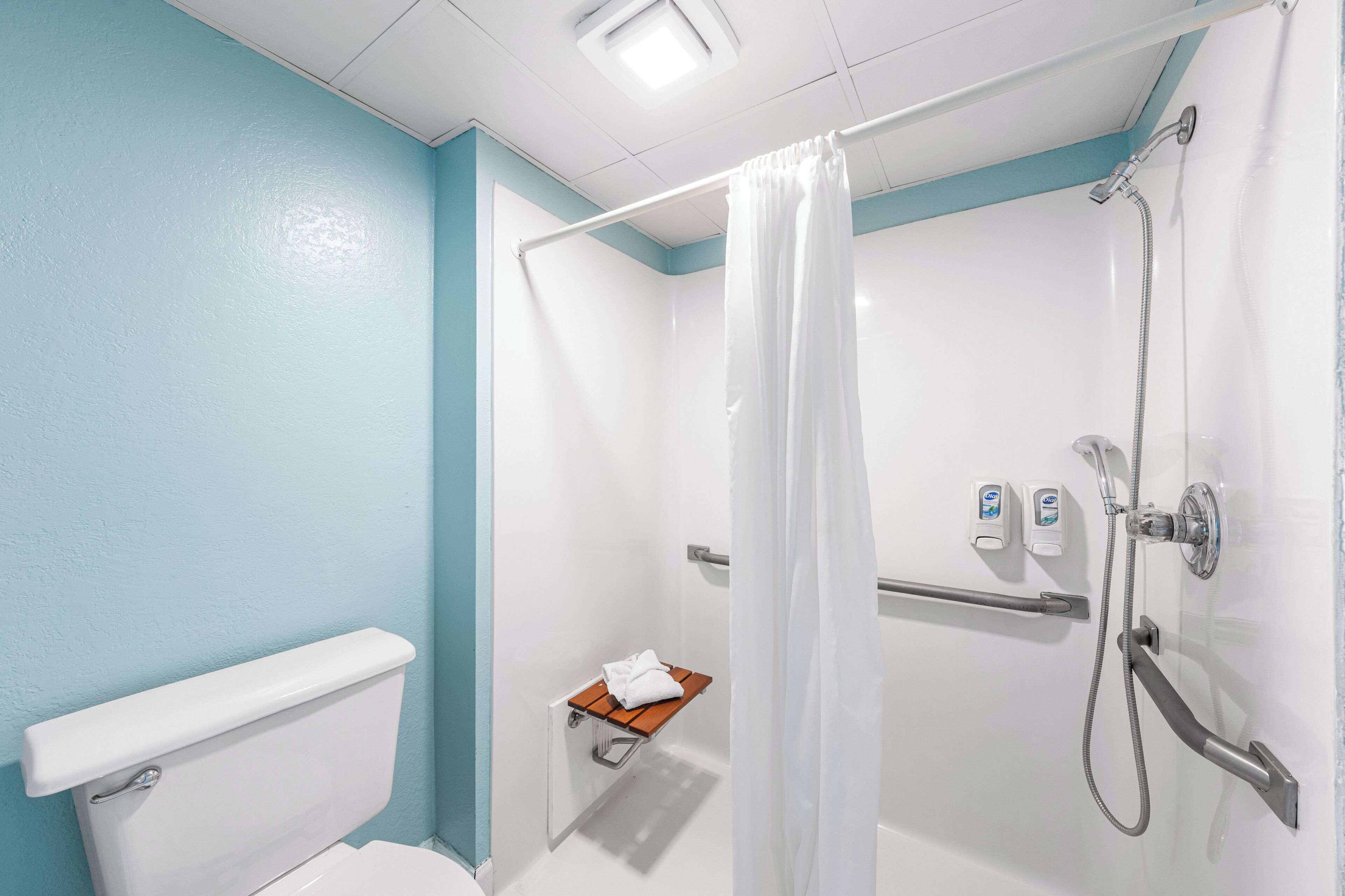Un baño con ducha, inodoro y un pequeño estante con una toalla.