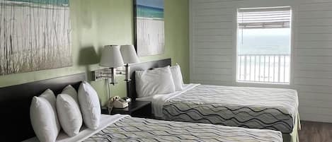A hotel room with two beds, a nightstand, a lamp, and artwork on the walls.