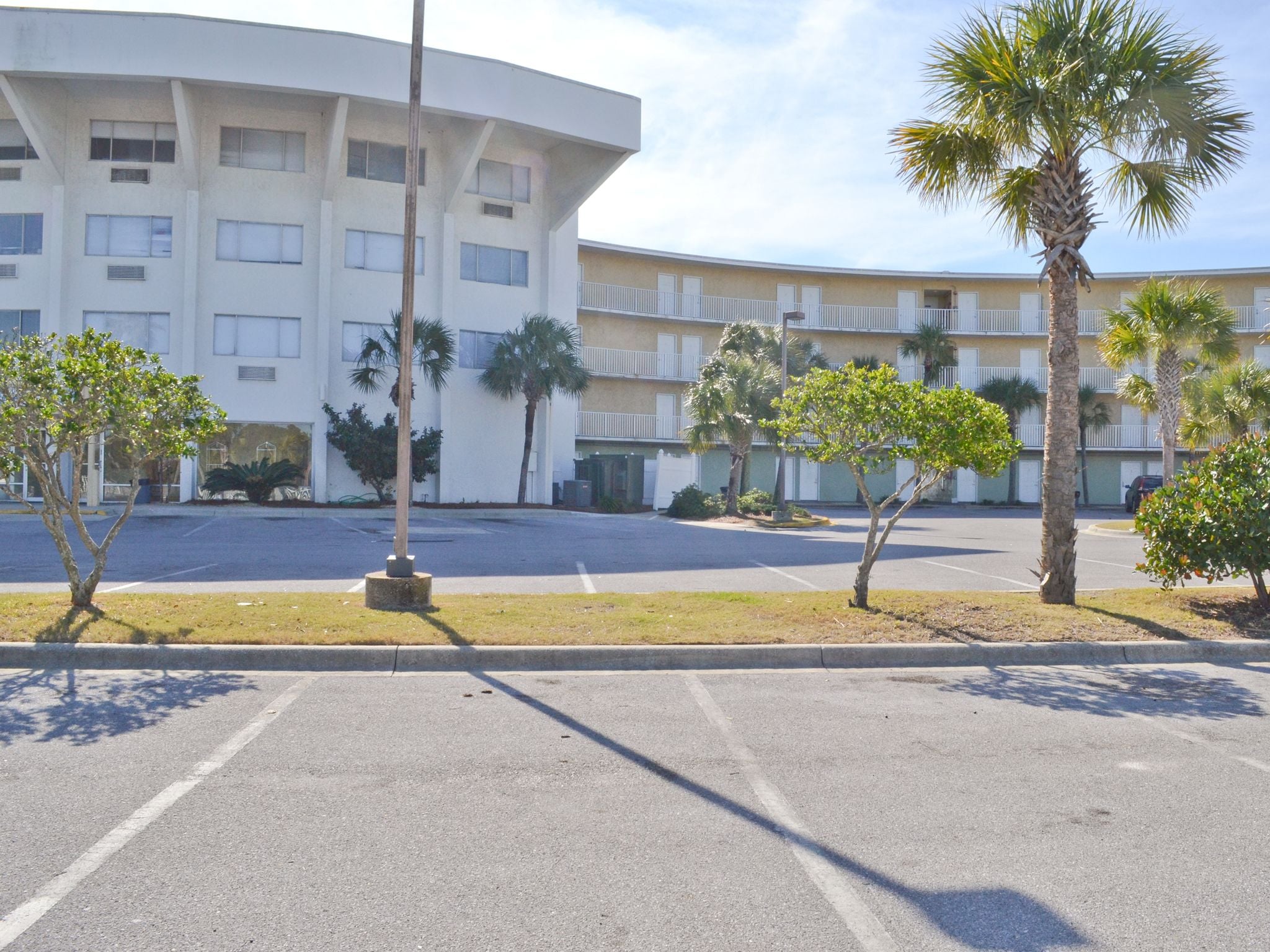 A parking lot with a building featuring a curved facade and multiple balconies.