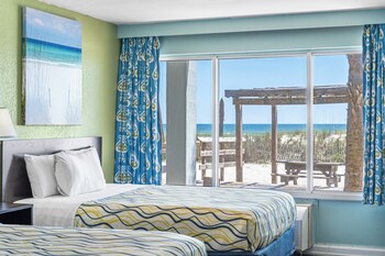 A modern building with a flat roof and a series of palm trees in front. at Boardwalk Beach Hotel