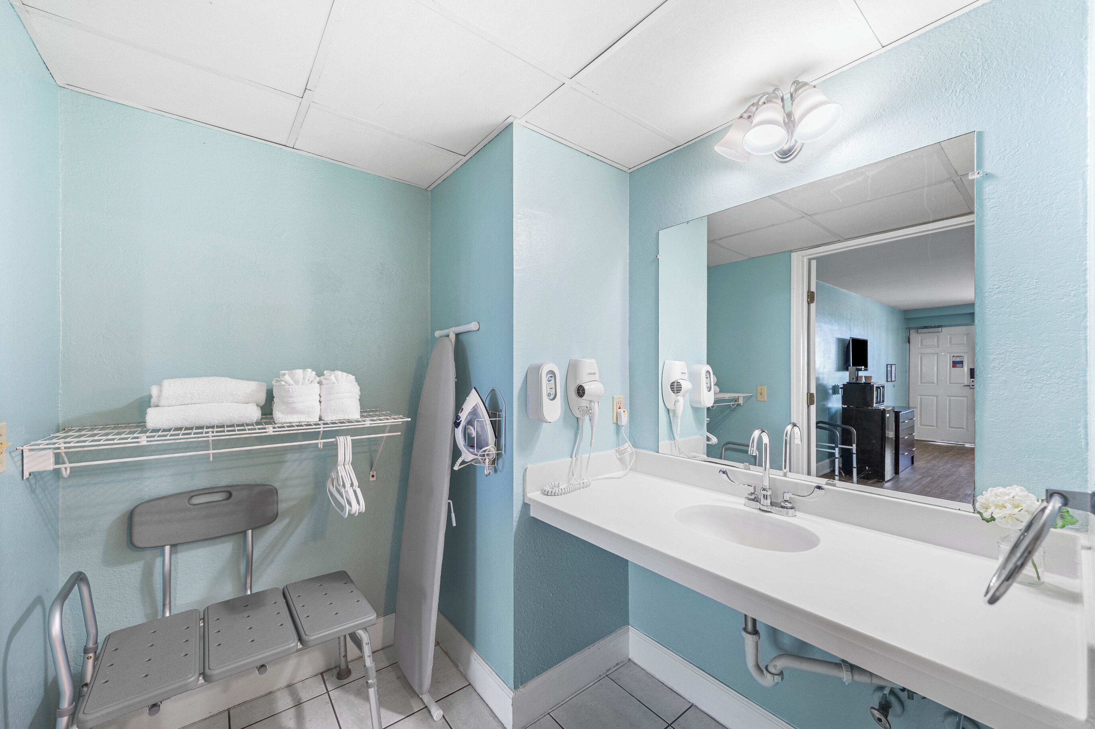 A bathroom with a large mirror, a white sink, and a towel rack.
