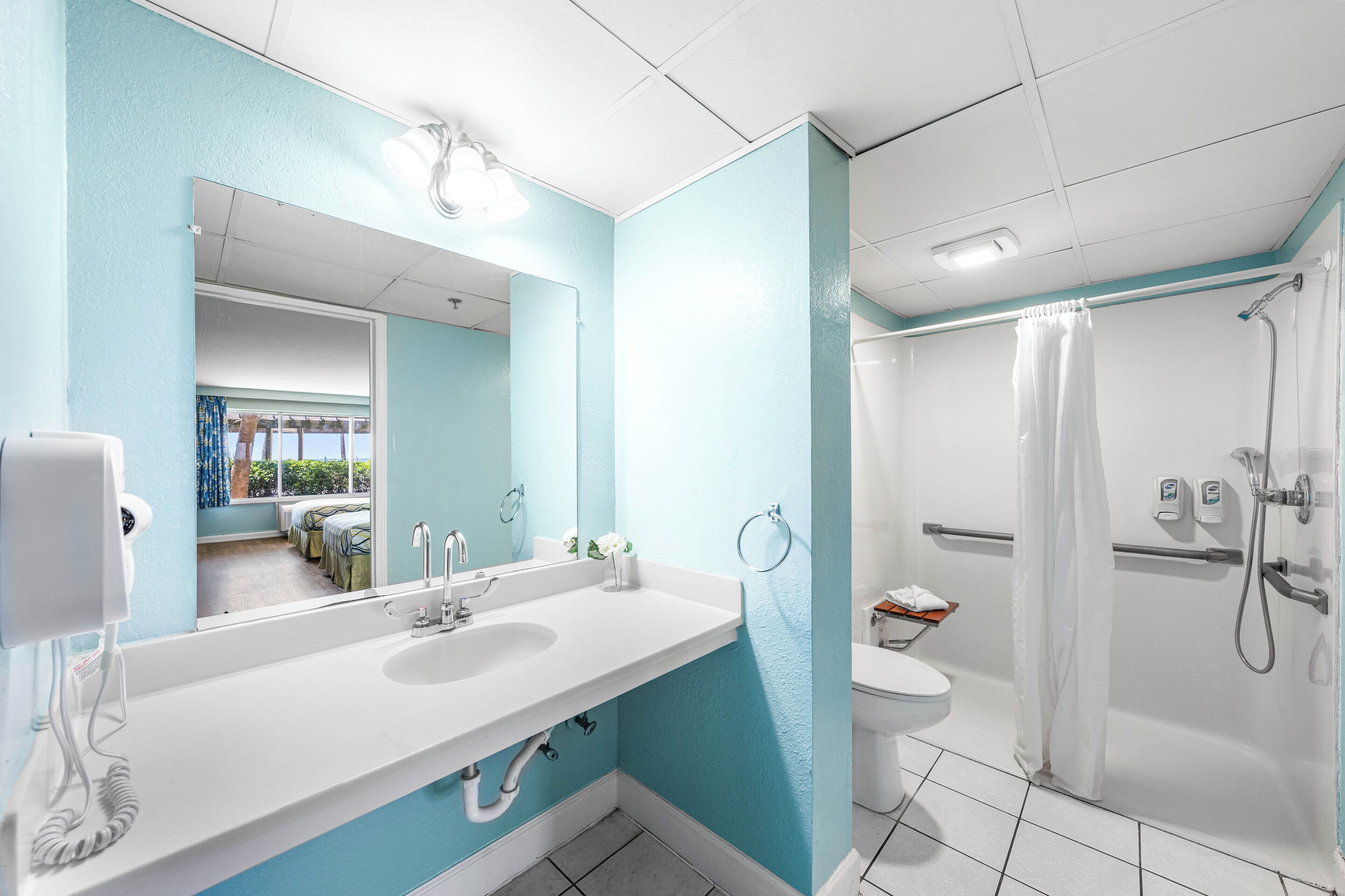 Un bagno con lavandino bianco, specchio e doccia.