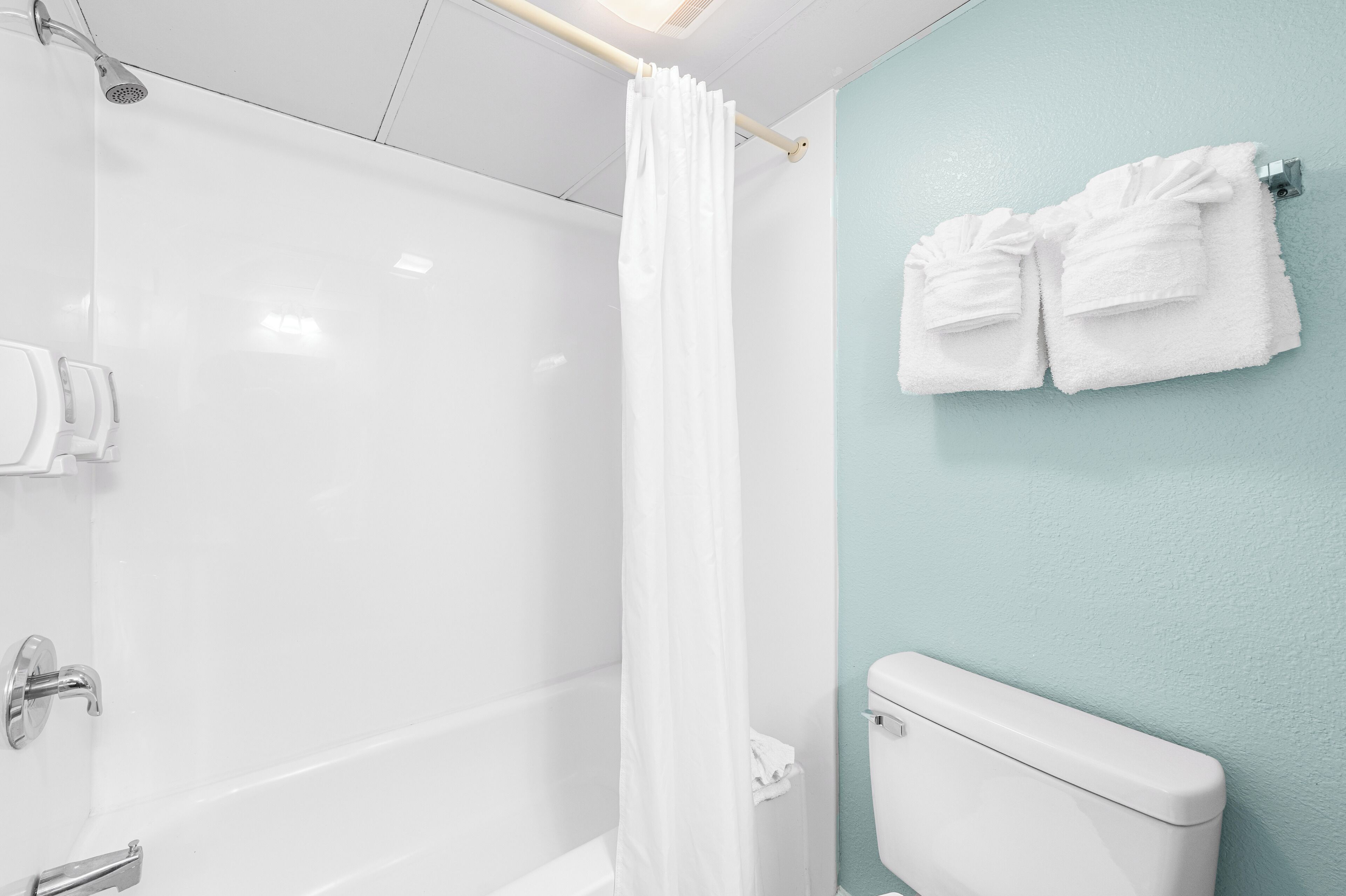 A bathroom with a shower, toilet, and towel rack.