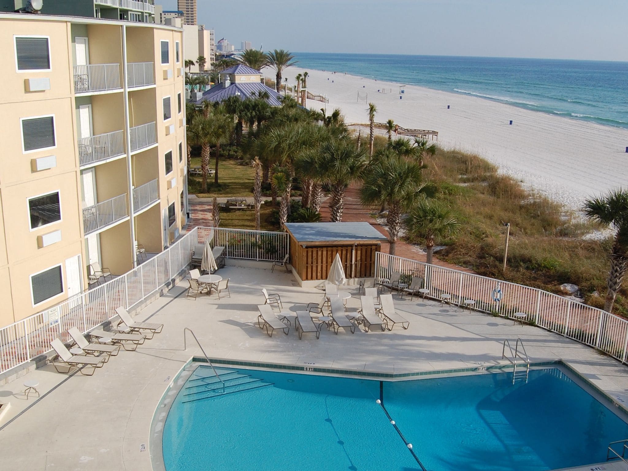A pool area with lounge chairs and a view of the beach.