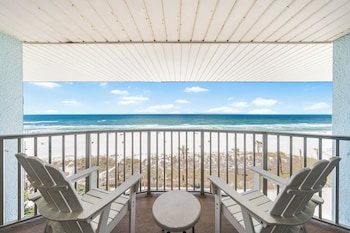 A room with a bed, a view of the beach, and a wooden pergola outside. at Boardwalk Beach Hotel