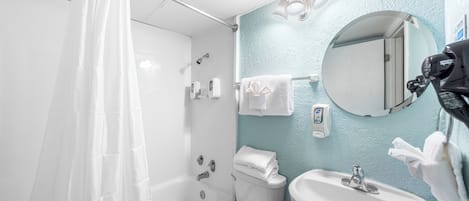 A bathroom with a bathtub, toilet, sink, and a mirror.